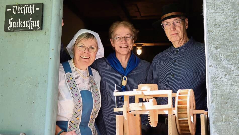 Anette Sellmann, Stefan Wiesner und Rolf Eggeringhaus vom Heimatverein Bad Westernkotten stehen in traditioneller Kleidung in der Tür der Schäferkämper Wassermühle neben einem Holzmodell des historischen Mahlwerks.